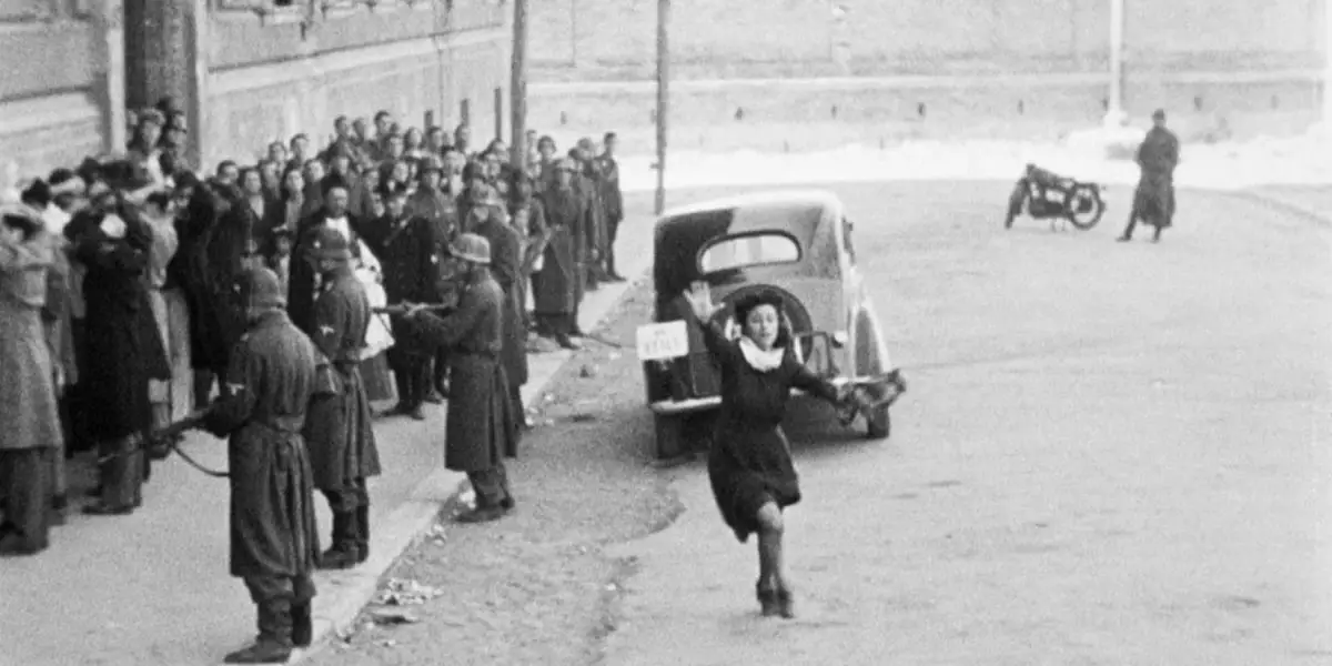 A girl running in through the street with her arm up in the film Rome, Open City