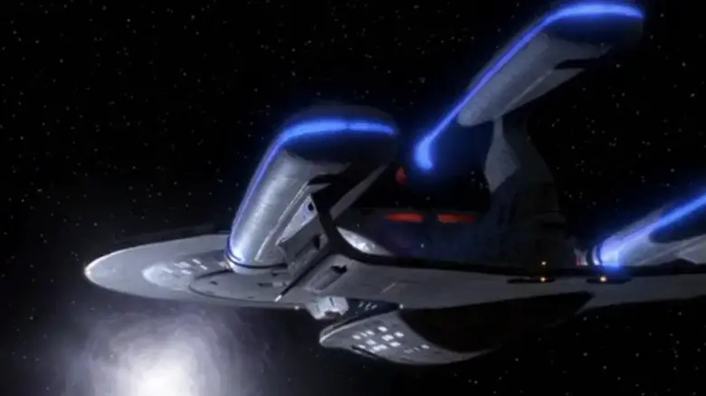The Enterprise-D with a third warp nacelle approaches a glowing spatial anomaly in Star Trek: The Next Generation