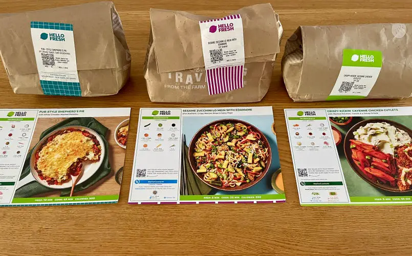 three HelloFresh meal cards and brown paper bags sitting on a counter.