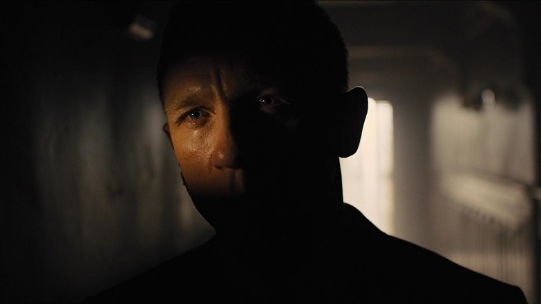 Daniel Craig as James Bond with most of his face cloaked in shadow in the opening scene of Skyfall