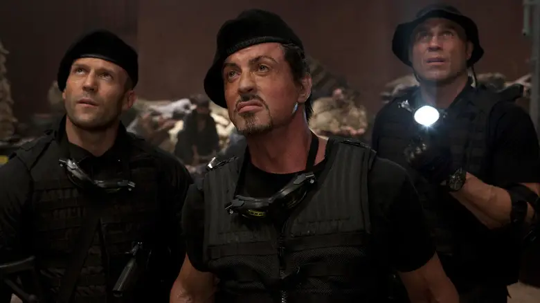 Jason Statham as Lee Christmas, Sylvester Stallone as Barney Ross, and Randy Couture as Toll Road in mercenary gear looking upward in The Expendables