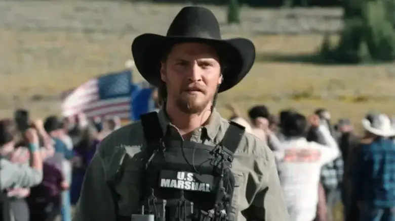 Luke Grimes as Kayce Dutton wearing a U.S. Marshal vest and his trademark cowboy hat on Marshals