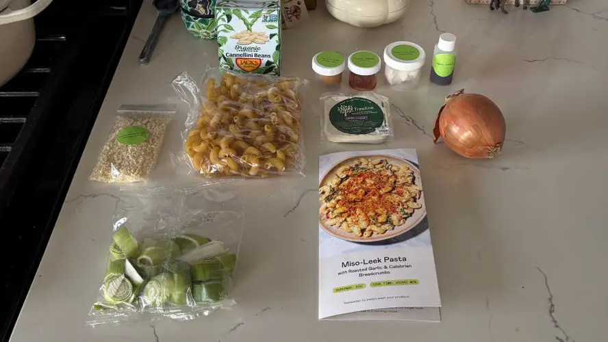 Purple Carrot Miso Leek Pasta Ingredients on white marble countertop next to black stovetop.
