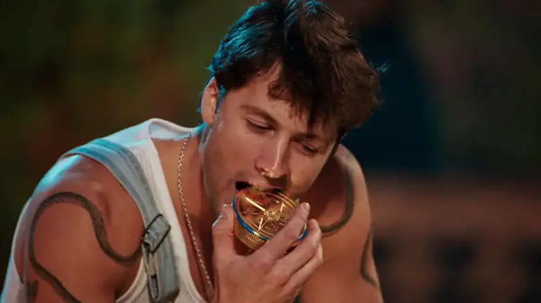 Rob biting one of his prop winnings coins on The Traitors