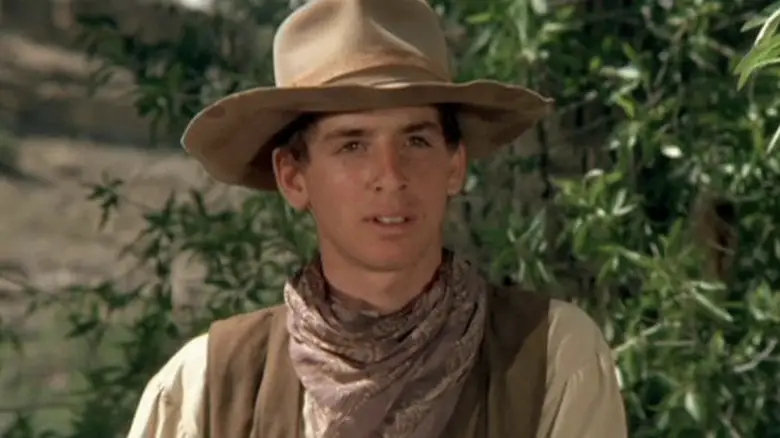 Robert Carradine's Slim Honeycutt looks across the frame as he stands outside in The Cowboys