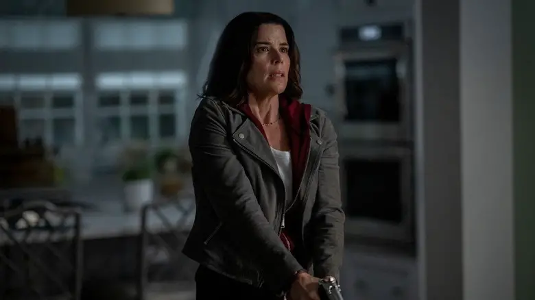 Neve Campbell as Sidney Prescott with a gun out in her kitchen in Scream 7