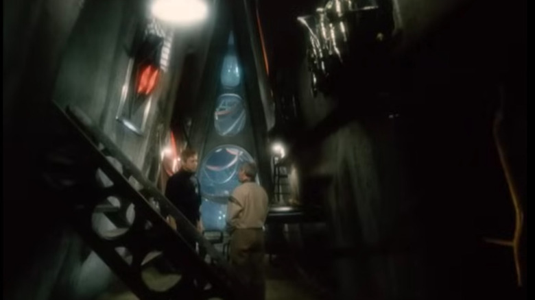 Oleg Vavilov as Andrew Harlan speaking to another man in a dark dystopian room in The End of Eternity