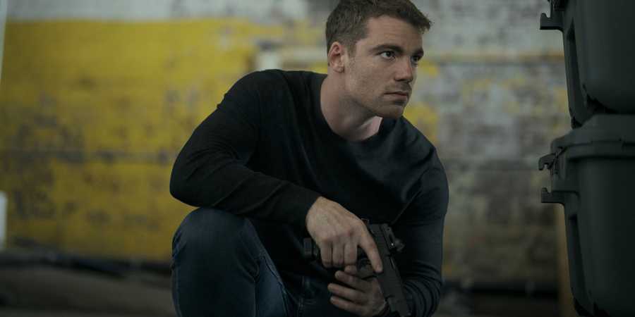 Gabriel Basso as Peter Sutherland crouching in The Night Agent season 3