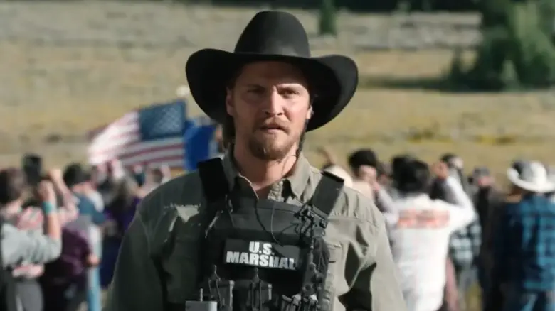 Luke Grimes as Kayce Dutton wearing a U.S. Marshal vest and his trademark cowboy hat on Marshals
