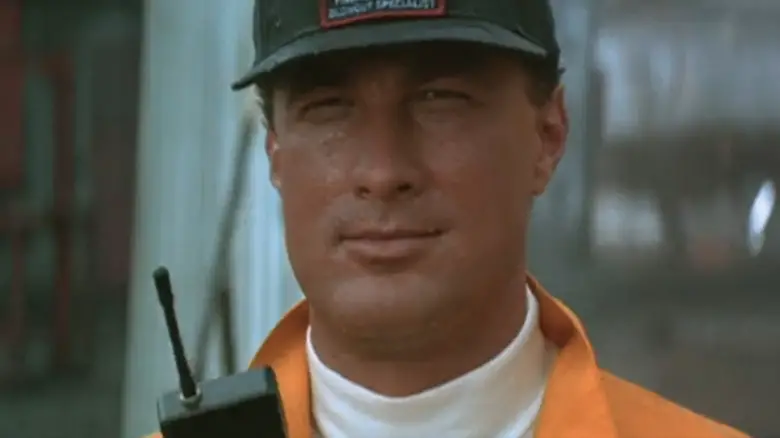Steven Seagal's Forrest Taft is seen in closeup holding a portable radio in On Deadly Ground