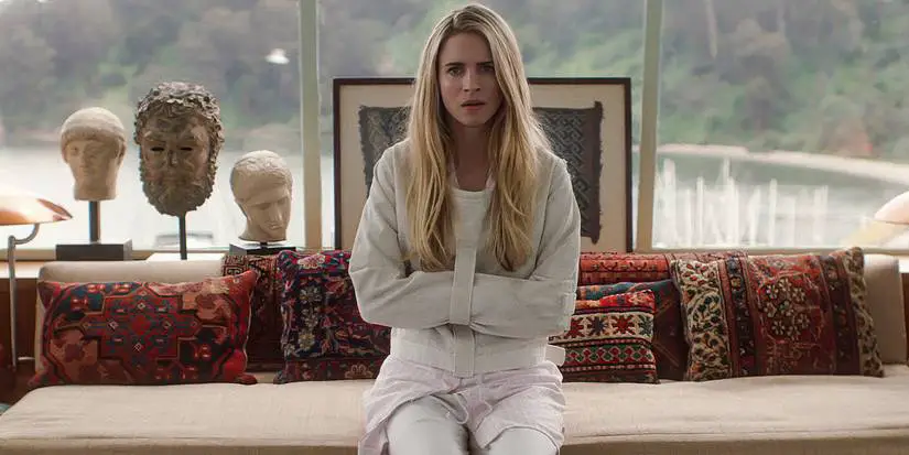 Brit Marling in a straitjacket sits on a couch in a house in The OA.