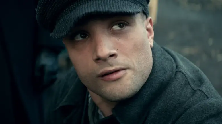 Cosmo Jarvis as Barney Thompson wearing a hat and looking up in Peaky Blinders