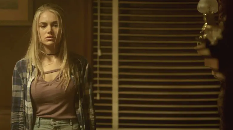 Michelle Randolph's Rachel standas looking worried in a dimly lit room in House of the Witch