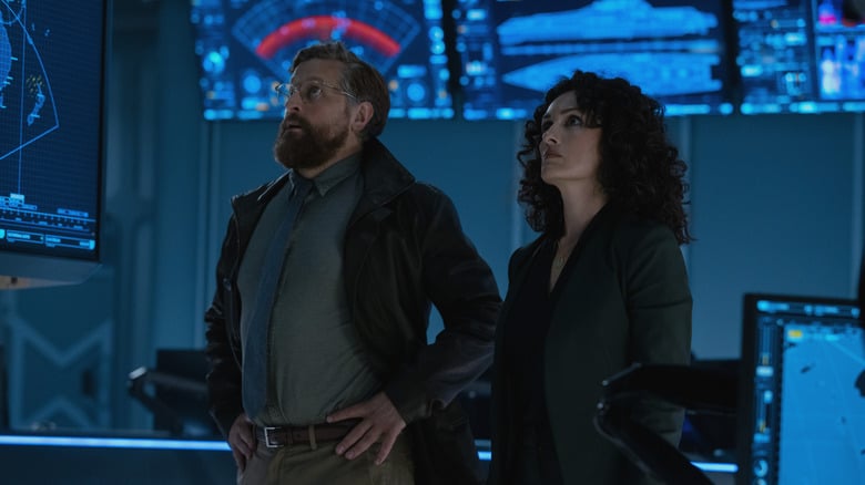 Joe Tippett as Tim and Mirelly Taylor as Natalia standing in the Monarch control center in Monarch: Legacy of Monsters season 2