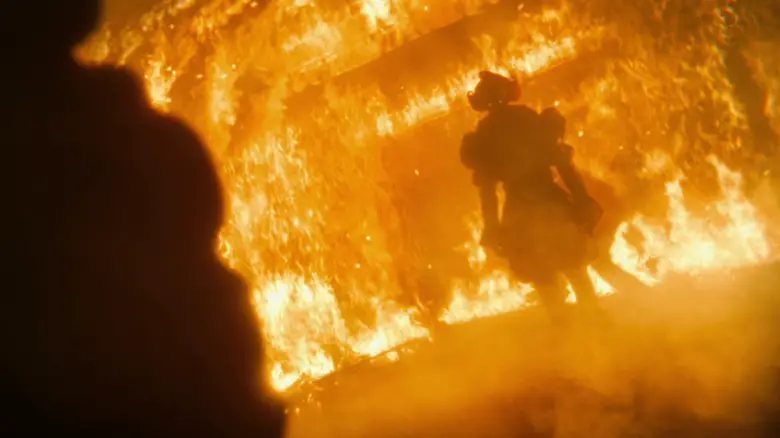 Bill Skarsgård's Pennywise stands in a fire in the Black Spot bar in It Welcome to Derry.jpg