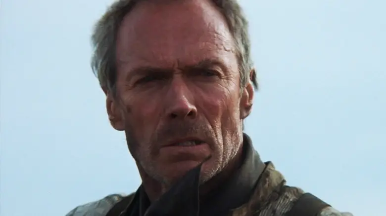 Clint Eastwood's Will Munny is seen in closeup against a blue sky in Unforgiven