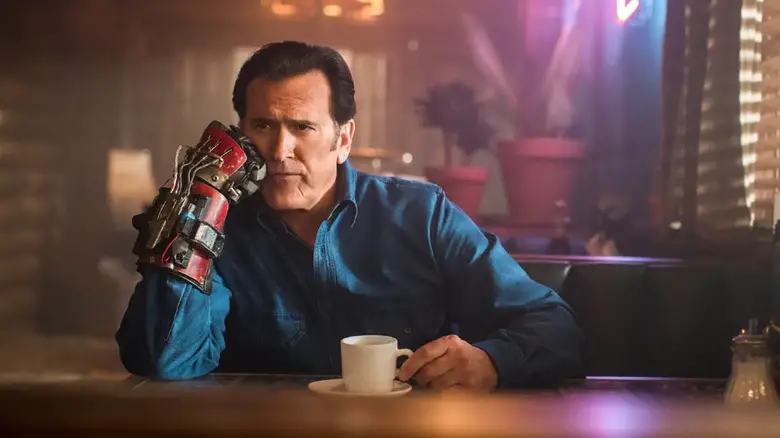 Bruce Campbell as Ash Williams in Ash vs the Evil Dead sitting at a diner table