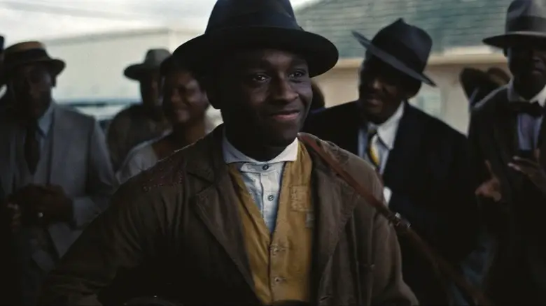 Sammie smiles as he plays his guitar in front of a crowd in Sinners