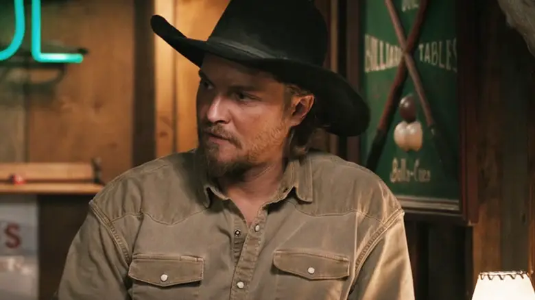 Luke Grimes' Kayce Dutton looks off to his right as he stands in a bar in Marshals