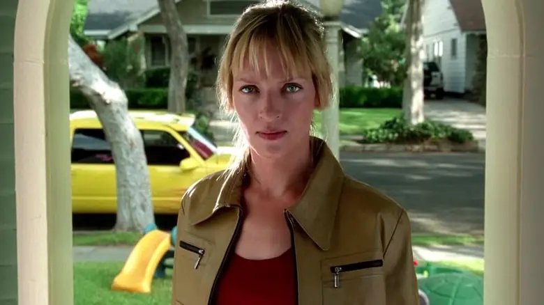The Bride standing in an open suburban doorway in Kill Bill