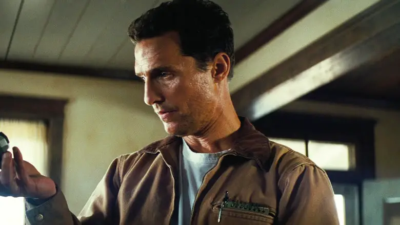 Matthew McConaughey's Joseph Cooper looks at something in his hand as he stands in his dining room in Interstellar.jpg