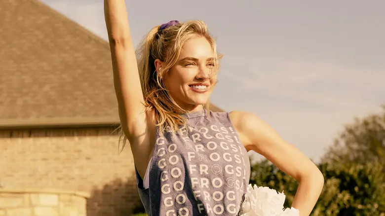 Michelle Randolph's Ainsley Norris smiles as holds up her pom-poms while standing in her back yard in Landman.jpg