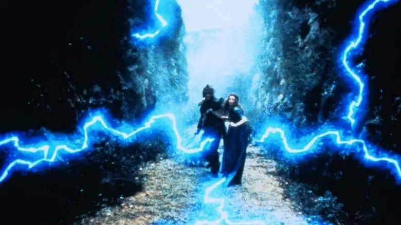 Liam Neeson's Grak and Rosalyn Landor's Guinevere stand amid blue lightning in Merlin and the Sword