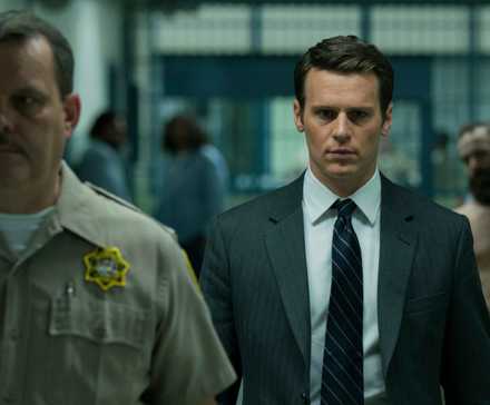 Holden walks down a prison hallways looking scared in Mindhunter