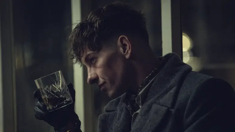 Barry Keoghan as Erasmus holding a glass of whiskey in Peaky Blinders: The Immortal Man