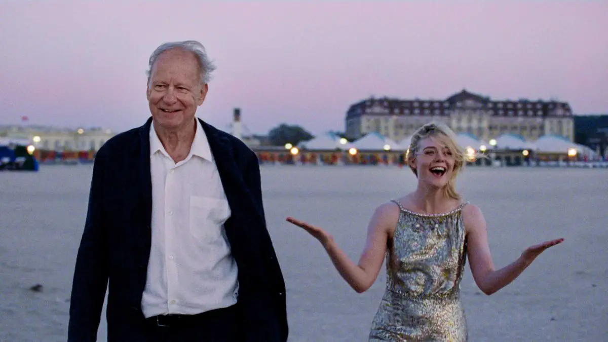 Stellan Skarsgård and Elle Fanning looking happy on a beach in Sentimental Value