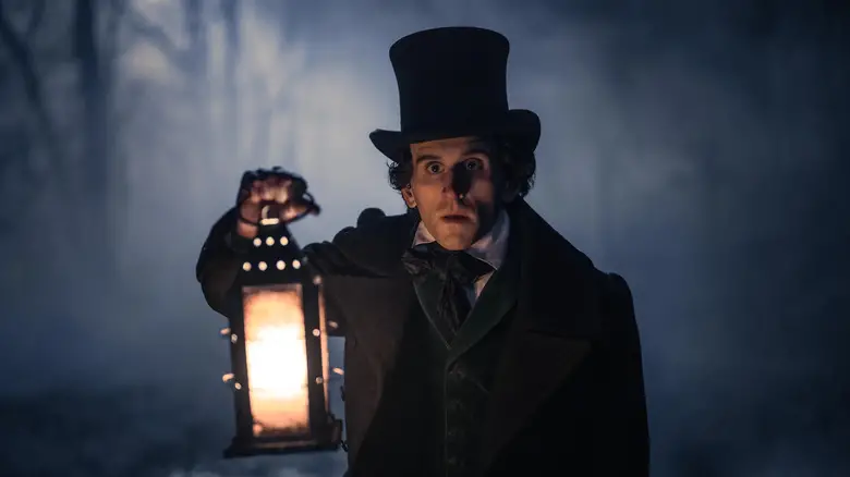 Edgar Allan Poe (Henry Melling) holds up a lantern in The Pale Blue Eye