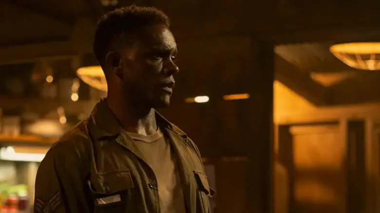 Chris Chalk's Dick Hallorann stands looking across a dimly lit room in It Welcome to Derry