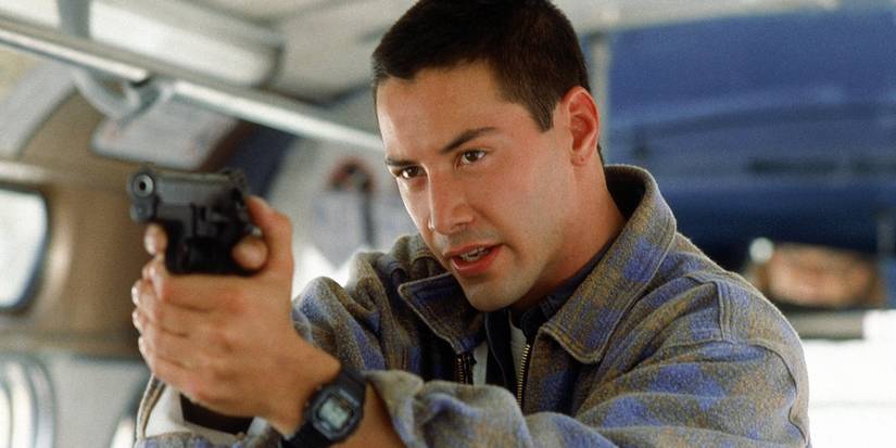 Keanu Reeves as Jack pointing a gun on a bus in Speed.